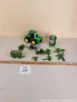 Full view of all included John Deere farm toys and story book beside a ruler and soda can for size reference