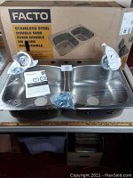 Front view of boxed sink, protective film intact, hardware and manual displayed