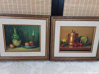 Pair of original oil paintings framed showing still life themes with ornate wooden frames and matting