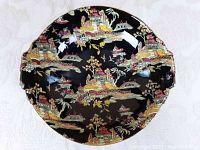 Top-down view showing full design of bowl with colorful Asian-themed pattern on black background, slight iridescence visible.