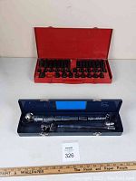 Two metal cases displayed open; red case with black sockets, blue case with chrome sockets and ratchets