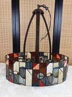 Front view of complete hanging light fixture showing stained glass shade and metal frame