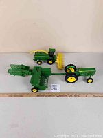 John Deere toy metal tractor with 348 baler and 6850 combine with removable plastic head, all on a white surface with ruler for scale