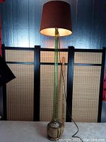 Full view of the vintage Chianti wine bottle floor lamp lit with mid-century style shade, showing height and ambient lighting effect