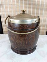 Front view of vintage wooden barrel-style ice bucket with brass handle and lid knob on top.