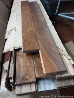 Opened box of walnut flooring planks showing board faces and finish