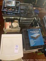 Overview of four plastic storage units with drawers containing various electronics and office supplies. Top drawers open showing cables and accessories, Analog Pass-Through DVD Converter Box visible.