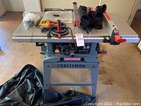 Full frontal view of table saw on rolling stand, cover bag on floor
