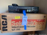 Mitsubishi VCR and remote on top of RCA SelaraVision VJT 700 box with 'Like New In Box' yellow label