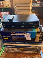 Stacked view showing unboxed Magnavox DVD/VCR recorder unit with remote on top, placed above boxed Sony and Panasonic units