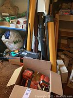 Shelf and floor view showing rod cases, rod handles, cardboard box and background items