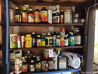 Full view of shelving unit with numerous bottles and containers of gardening chemicals and a white handheld sprayer on bottom shelf.