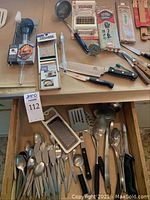 Overview of silverware and multiple kitchen utensils including slicers, spoons, knives and a candy thermometer