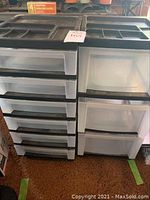 Three plastic drawer units side-by-side showing clear drawers and black organizer trays on top.