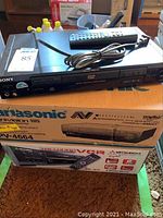 Sony DVD player with remote on top of Panasonic and Mitsubishi boxes