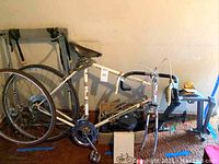 Overall lot view showing Peugeot road bike, box of supplies, floor pump, and indoor trainer