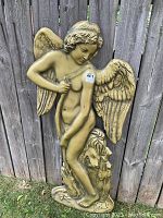 Full view of the vintage gold relief wall sculpture showing the angel standing with wings spread and the lion sitting at the base.