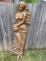 Full view of the tall vintage copper-tone fiberglass composite relief wall sculpture of a woman carrying a water jug, showing condition and details.