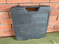 Closed black hard plastic carrying case branded Mastercraft, with handle and textured surface.