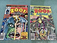 Front covers of two Marvel Comics 2001: A Space Odyssey issues no. 2 and no. 8 side by side on a blue surface.