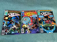 Three comic books laid side by side on a blue fabric surface showing issues 5, 10 and 11 of Marvel Spotlight on Captain Universe.