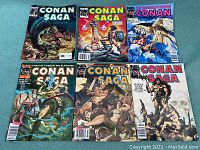 Six Conan Saga and The Savage Sword of Conan comics laid out showing front covers with detailed artwork depicting Conan in different fantasy scenes.