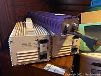 Three ballasts arranged on a wooden surface, showing the 600W and 1000W Sunleaves Luma 3.0 ballasts and the purple Super Lumens ballast.