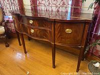 Front and angled views of a wooden buffet displaying polished wood finish, brass pulls, and side cabinets