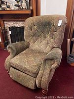 Reclining chair with floral upholstery shown from front angle. Upholstery is worn, seat cushion loose, and footrest partially extended.