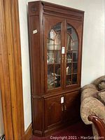 Full view of corner cabinet angled in a room, showing wood finish and design details