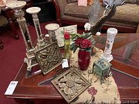 Table with all items including eagle statue, three candle pillars, red vase with flowers, green lantern, two metallic wall plaques, porcelain vase, decorative Bible, table runner.