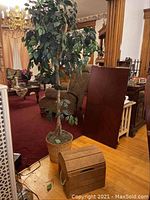 65-inch tall faux leafy tree in woven basket planter next to wooden trunk box.