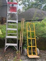 Overview of Werner 6ft aluminum Saf-T-Master ladder, yellow hand truck, and Seymour post hole digger in outdoor setting.