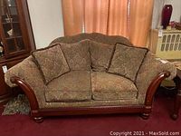 Front view of patterned fabric loveseat with wooden armrests and cushions