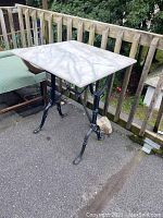 Full front-side view of the marble top table with cast iron base, showing overall condition and design.