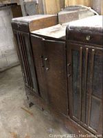 Front and side view of the vintage brown wooden cabinet showing glass panel doors, small drawers, and wooden doors with visible surface scratches.
