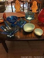 Blue glass serving dishes alongside light blue Fire King oven bowls arranged on wooden table.