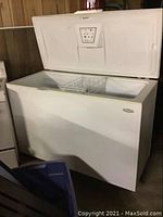 Front view of Wood's chest freezer with lid open showing interior and wire basket, exterior dent visible