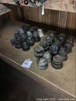 Photo showing multiple glass and porcelain electrical insulators arranged on a wooden table, varying in shape, size, and color.
