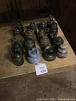 Overview of 16 glass electrical insulators of various sizes and colors arranged on wooden surface.