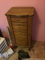 Frontal view of wooden jewelry cabinet showing 8 drawers and side doors.