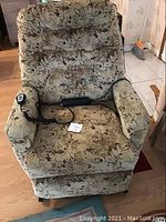 Front view of the power recliner upholstered in patterned fabric with remote control on seat