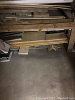 Wood pile on a basement bench showing assorted boards and slabs