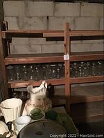 Wooden shelving with two rows of various sizes of clear glass mason jars with metal lids.