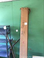 Boxed Diplomat Tripod Projector Screen leaning against a green wall with some visible wear and tear on the box.