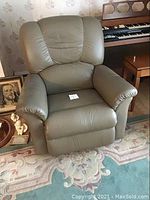 Front view of the tan leather recliner chair showing padded seat and arms.