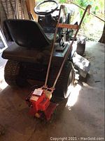 Front view of handheld rototiller with engine and handlebars