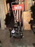 Full view of Macleods rototiller with handlebar, engine, and frame showing. Red decal on handlebar with branding.