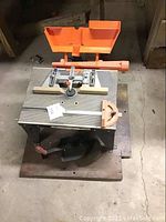 Full view of the Sears Craftsman router table on wooden base, showing metal ribbed tabletop, orange safety guard, and adjustable fence.
