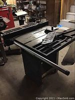 Full view of table saw with rip fence rails and metal bracket on tabletop